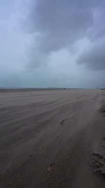 Fırtınalı sahil manzarası, çalkantılı bulut örtüsünün altındaki ıssız kıyı şeridi, dalgalar ve uzak deniz kenarları.