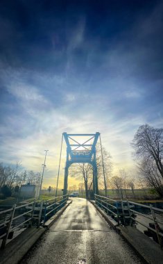 Gün batımında asma bir köprünün çarpıcı manzarası güzelliği ve mimari çekiciliği vurguluyor.