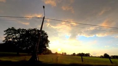 Gün batımında sakin tarlalar, canlı gökyüzü, sakin kırsal manzaralar karanlık topraklar ve canlı günbatımı gökyüzü