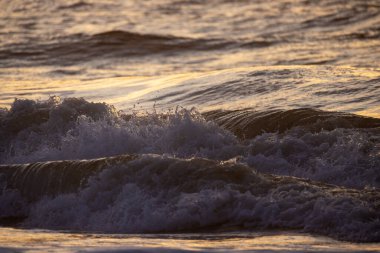 Gün batımı gökyüzünü renklendirir ve okyanus dalgalarını aydınlatır. Gece yaklaşırken sakin bir atmosfer yaratır.