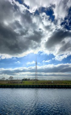 Canlı bulutlar ve yemyeşil yeşilliklerin sergilendiği huzurlu ve huzurlu bir nehir manzarası.