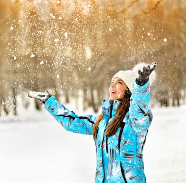 woman blowing snow in winter park