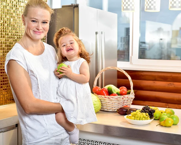 Jovem mãe feliz com um bebê na cozinha — Fotografia de Stock