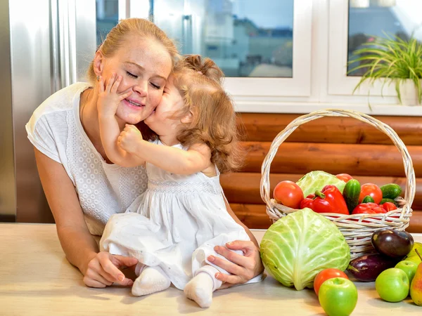 Jovem mãe feliz com um bebê na cozinha — Fotografia de Stock