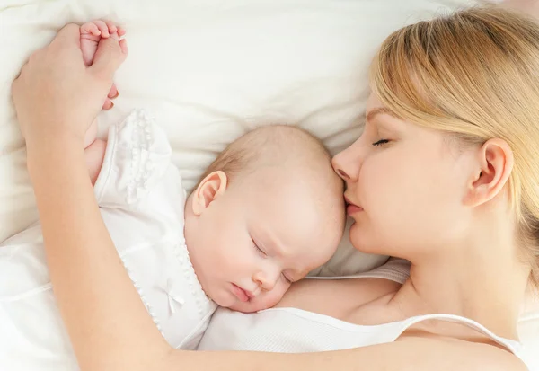 Jeune mère et son bébé dormant au lit — Photo