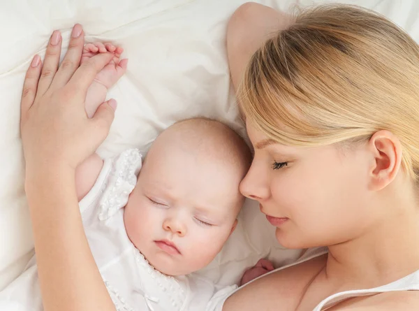 Jeune mère et son bébé dormant au lit — Photo