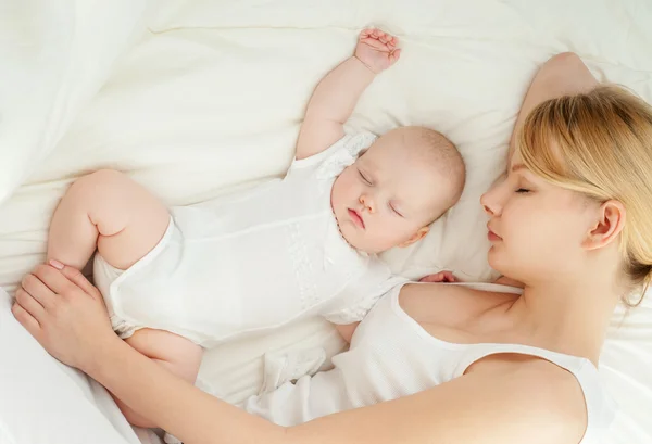 Jonge moeder en haar baby slapen in bed — Stockfoto