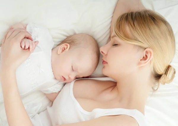 Joven madre y su bebé durmiendo en la cama — Foto de Stock