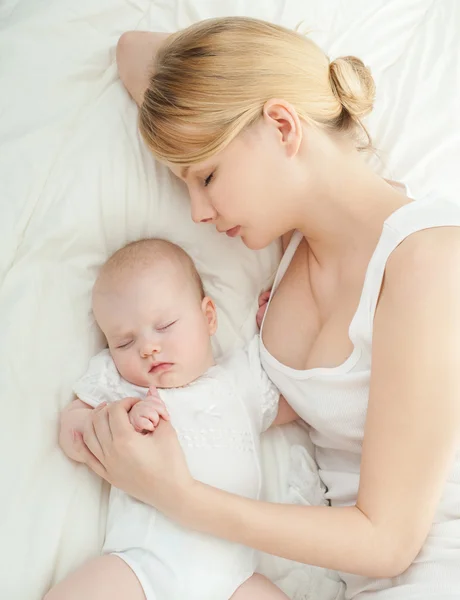 Jeune mère et son bébé dormant au lit — Photo