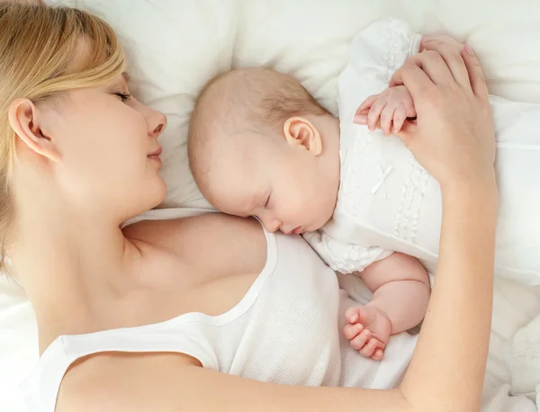 Joven madre y su bebé durmiendo en la cama — Foto de Stock