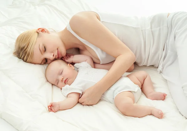 Jeune mère et son bébé dormant au lit — Photo