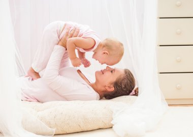 Anne ve bebek oynuyor ve gülümsüyor.