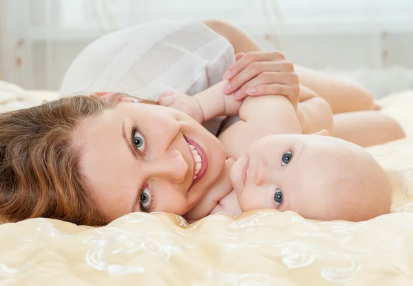 Мать и ребенок играют у кровати — стоковое фото