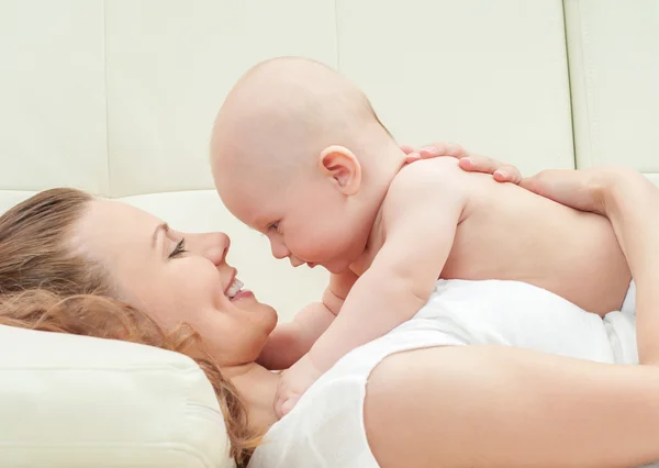 Mother and baby playing on sofa Stock Picture