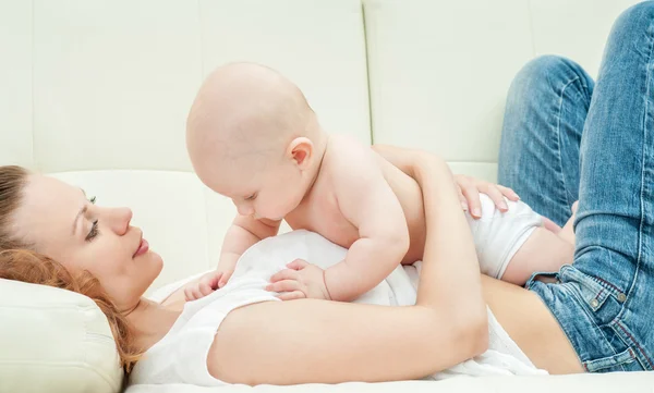 Mother and baby playing on sofa Royalty Free Stock Photos