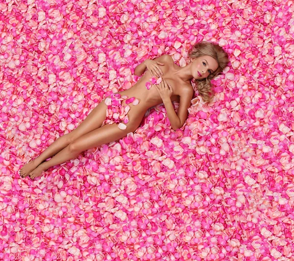 Woman lying on petals of pink roses — Stock Photo, Image