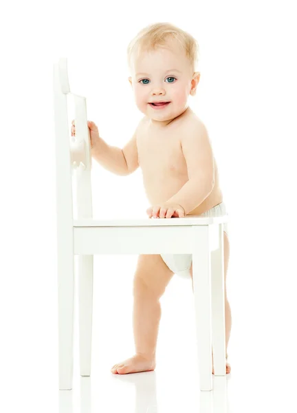 Baby holds on to a white chair — Stock Photo, Image