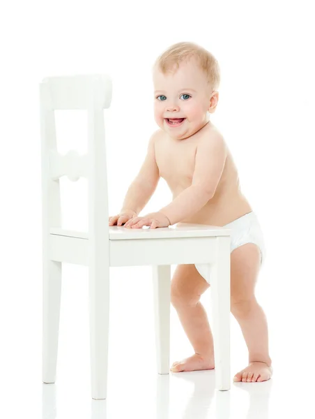 Baby houdt vast aan een witte stoel — Stockfoto