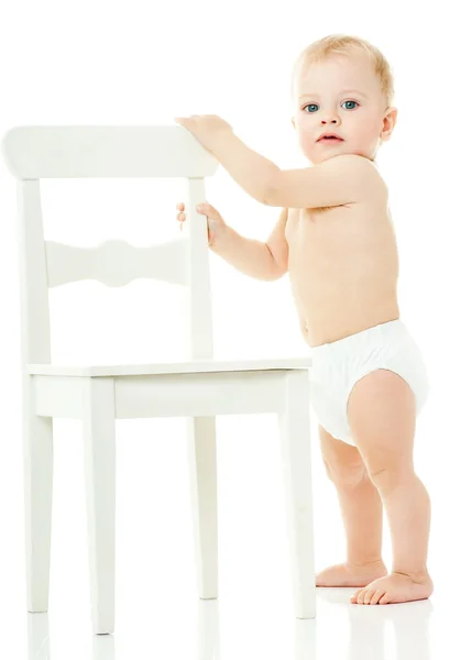 Bebê segura em uma cadeira branca — Fotografia de Stock