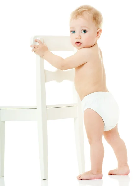 Dziecko trzyma się białe krzesło — Zdjęcie stockowe