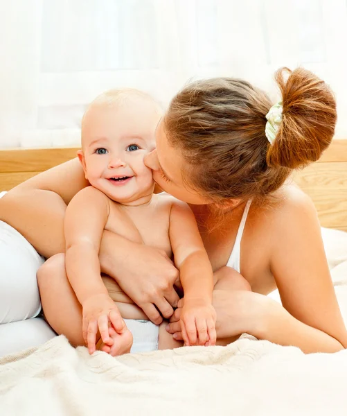Mother and baby playing at bed Stock Image