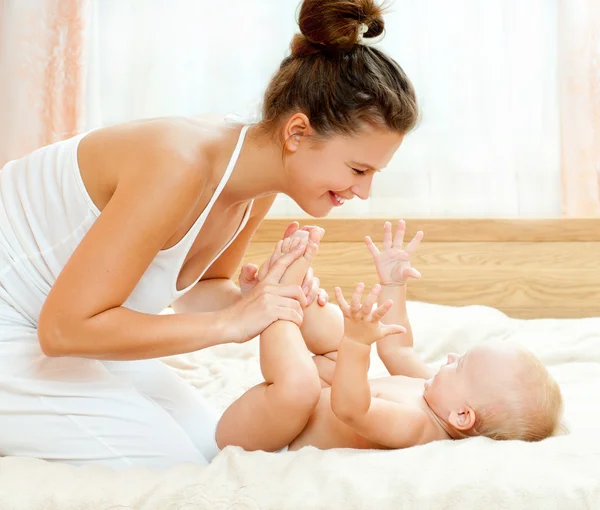 Moeder en baby spelen op bed — Stockfoto