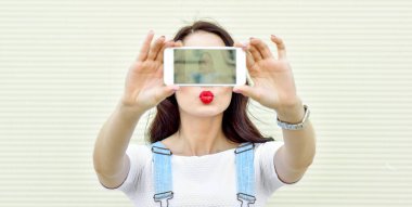 Güzel bir kız akıllı telefondan kendi portresini, ekran görüntüsünü çekiyor.