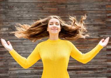 Güzel gülümseyen esmer kadın, ahşap arka planda lüks saçları olan. Sonbahar geldi. Sonbahar sezonu.