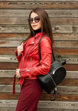 Ahşap arka planda güneş gözlüklü, gülümseyen güzel esmer kadın. Sokak modası. Açık havada..