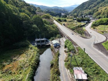 Nehir üzerinde köprüsü olan bir yol. Köprü küçük bir kasabaya yakındır. Yol boş.