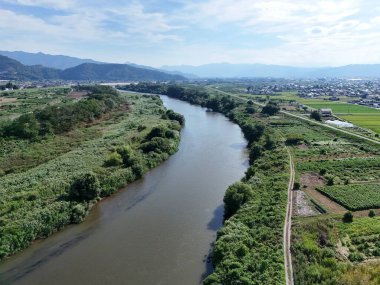 A bridge spans a river in a lush green valley. The bridge is surrounded by trees and the valley is full of greenery