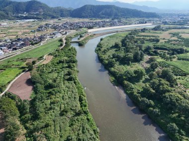 A bridge spans a river in a lush green valley. The bridge is surrounded by trees and the valley is full of greenery