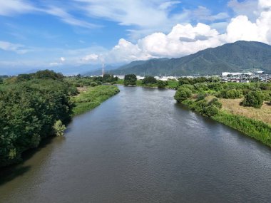 A bridge spans a river in a lush green valley. The bridge is surrounded by trees and the valley is full of greenery