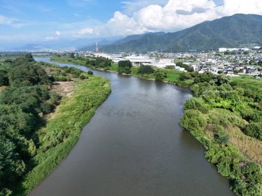 A bridge spans a river in a lush green valley. The bridge is surrounded by trees and the valley is full of greenery