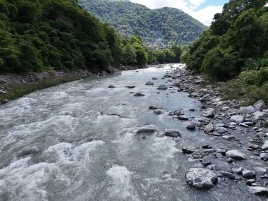 A river with a lot of rocks in it. The water is moving fast and the rocks are scattered throughout the river