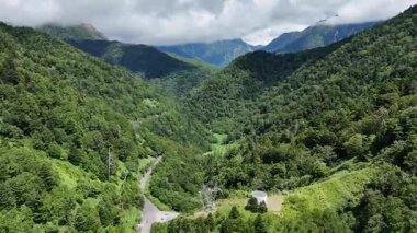 Bulutlu gökyüzünün altında yemyeşil dağlar ve vadiler