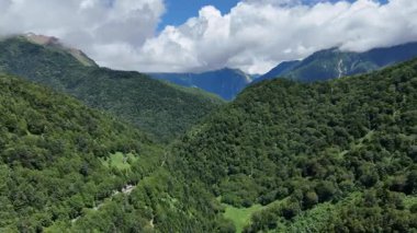 Parlak mavi gökyüzünün altında yemyeşil dağlar
