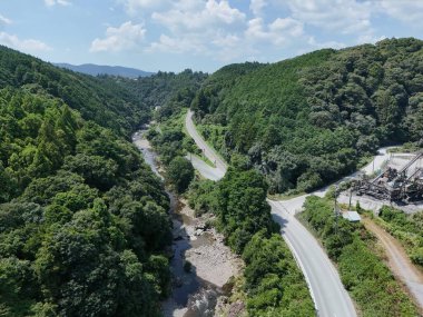 Yanı başında nehir akan bir dağ yolu. Yol dolambaçlı ve dar, ve ağaçlar yemyeşil