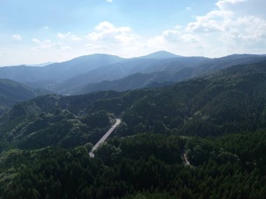 Dağlar ağaçlarla örtülmüş, gökyüzü de berrak. Manzara nefes kesici ve huzur verici. Dağlar güzel ve huzurlu bir manzara.
