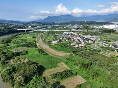 Nehir ve köprüsü olan yeşil bir manzara. Köprü bir nehrin üzerinde ve manzara ağaçlarla dolu.