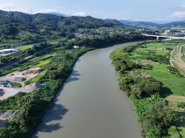 Üzerinde köprü olan bir nehir ve diğer tarafında yeşil bir alan. Nehir kahverengi, köprü beyaz.