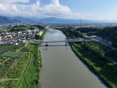 Üzerinde köprü olan bir nehir ve arka planda bir kasaba. Köprü çok uzundur ve nehrin tüm genişliğini kapsar.