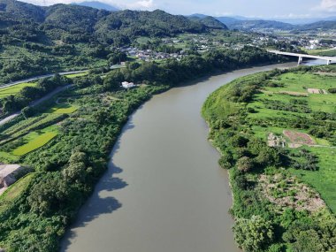 Üzerinde köprü olan bir nehir ve diğer tarafında yeşil bir alan. Nehir kahverengi, köprü beyaz.