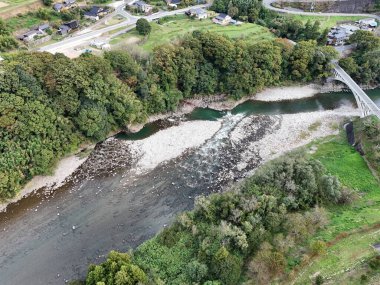 Üzerinde köprü ve her iki tarafında ağaçlar olan bir nehir. Nehir taş ve enkaz dolu.