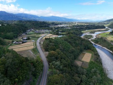 Bir şehrin arka planında güzel bir dağ sırası görülebilir. Şehir bir nehir ve bir ormanla çevrilidir. Manzara sakin ve huzurlu, dağlarla birlikte.
