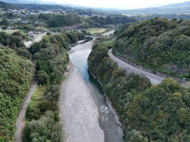 İçinden nehir akan güzel bir dağ manzarası. Ağaçlar yemyeşil, gökyüzü berrak. Sahne huzurlu ve huzurlu, nehir vadiden sakince akıyor.