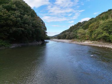 Temiz mavi suyu ve arka planda ağaçları olan bir nehir. Su sakin ve huzurlu.