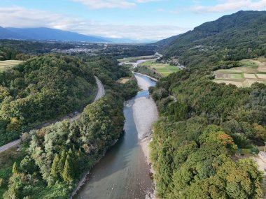 Arkasında dağ olan yemyeşil bir vadiden bir nehir akıyor. Huzurlu ve huzurlu bir manzara. Su vadiden sakince akıyor.