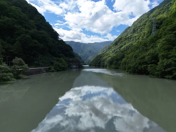 Arka planda bulutlu bir gökyüzü olan bir nehir. Su yeşil ve gökyüzünün yansıması görülebilir.