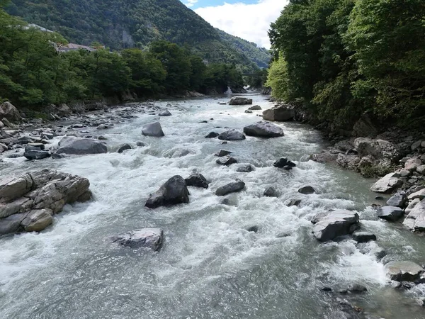 İçinde bir sürü taş olan bir nehir. Su çok berrak ve kayalar nehrin dört bir yanına dağılmış.